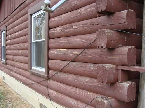 Log home cleaning & restoration. Side of log cabin before paint removal