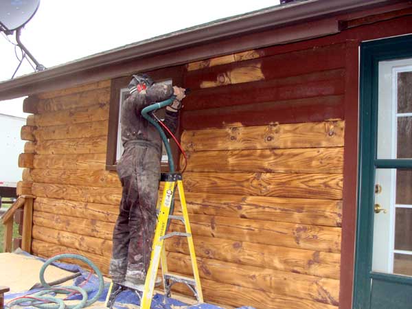 Log home cleaning & restoration. Technician removes paint from log home