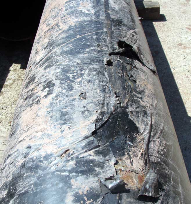 Oilfield pipe covered with protective fabric wrapping that needs to be removed