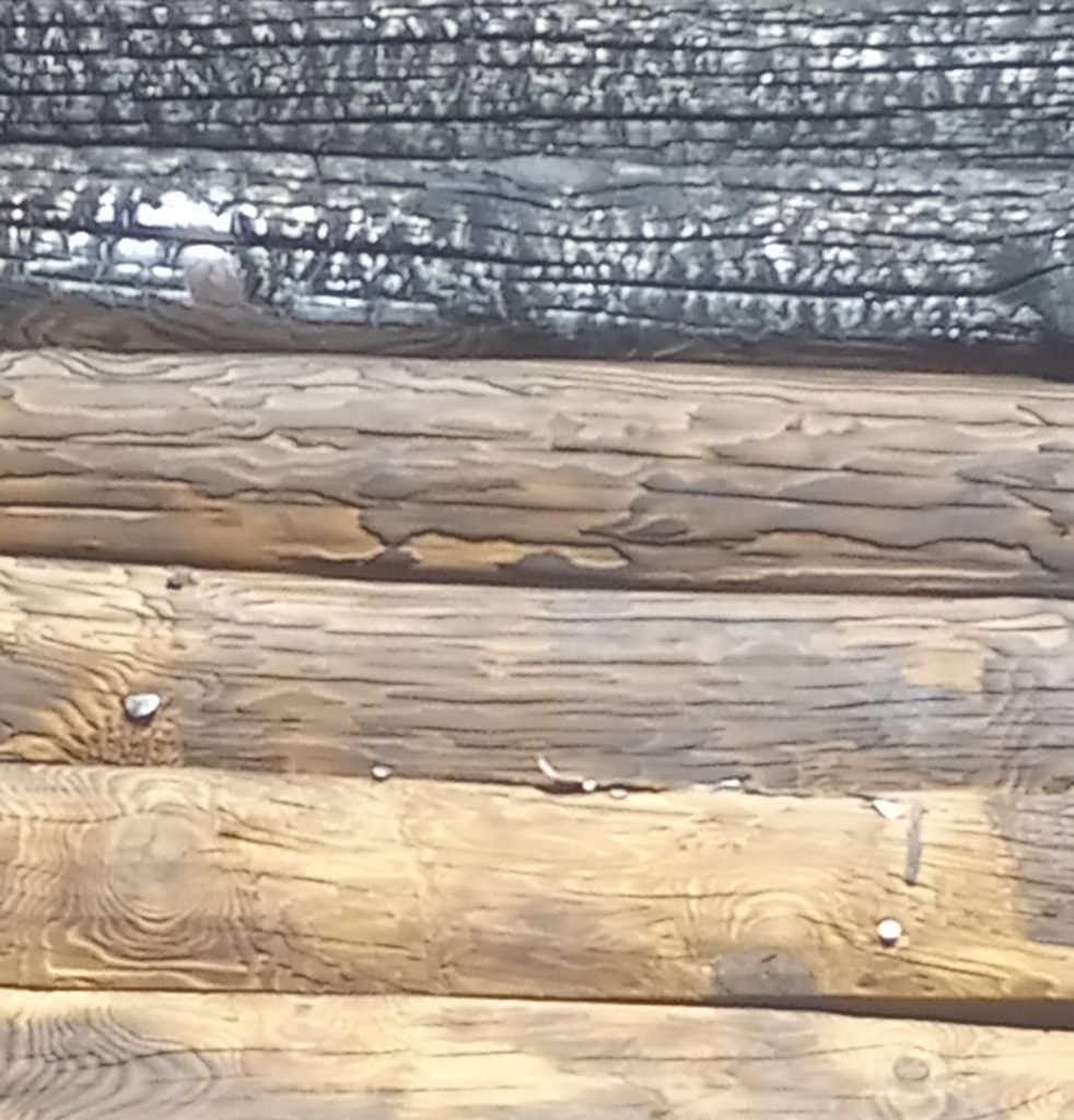 Log home cleaning & restoration. Before and after photo of fire-damaged log home during soda blasting.